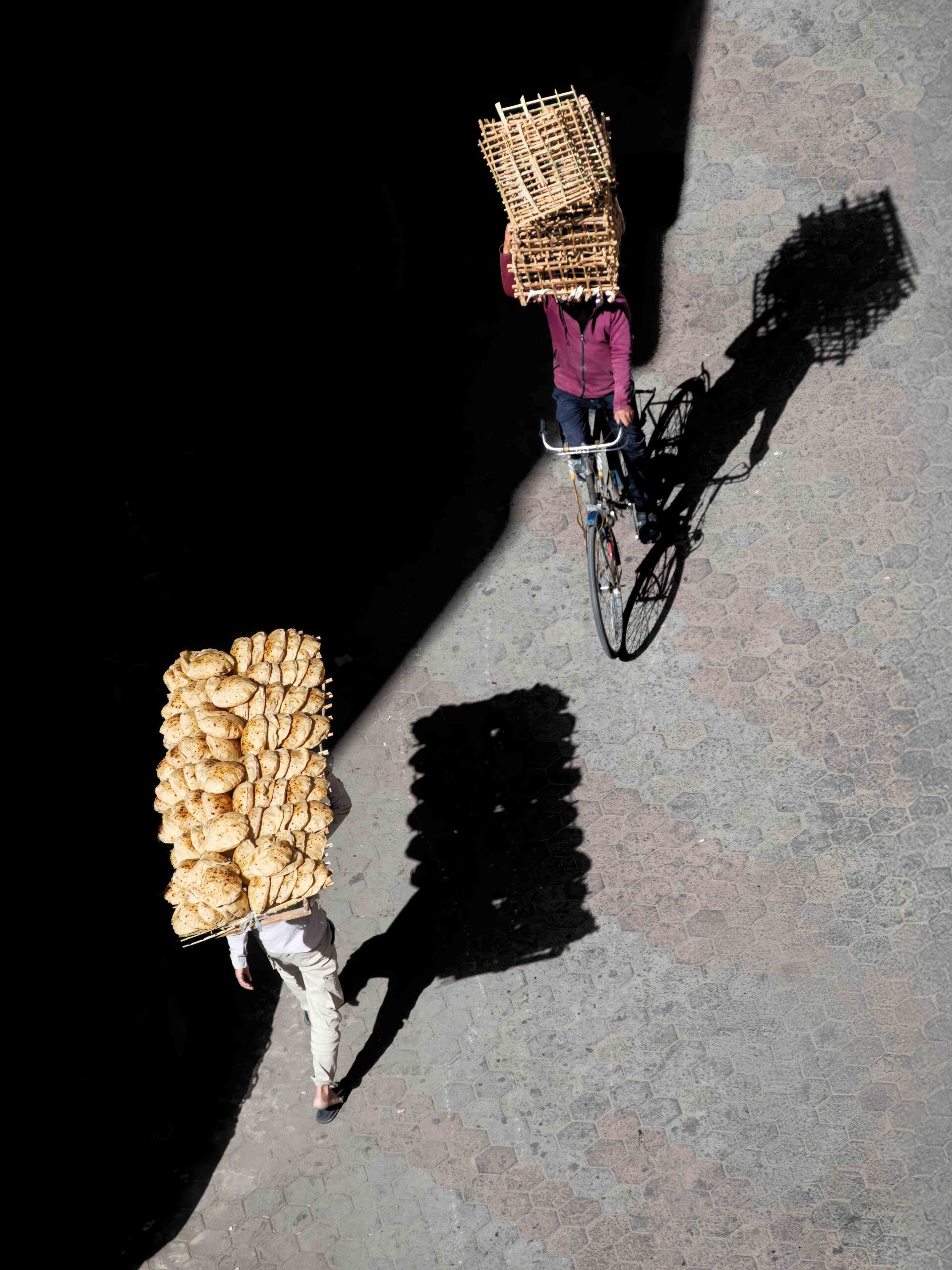 Ahmed Abdallah — Cairo, Egypt. Bread carriers move through the streets of Cairo beneath strong sunlight, creating striking geometric shadows.