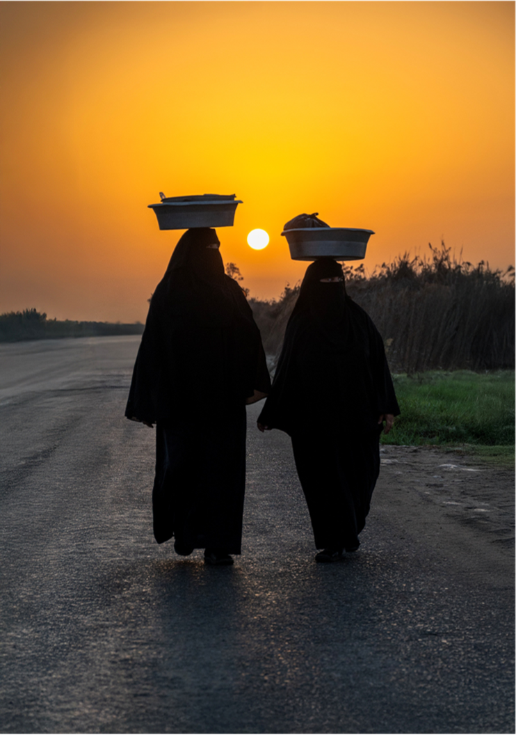 Ahmed Abdallah — Burullus, Egypt. Two women walk along a rural road at sunset, balancing their loads on their heads.