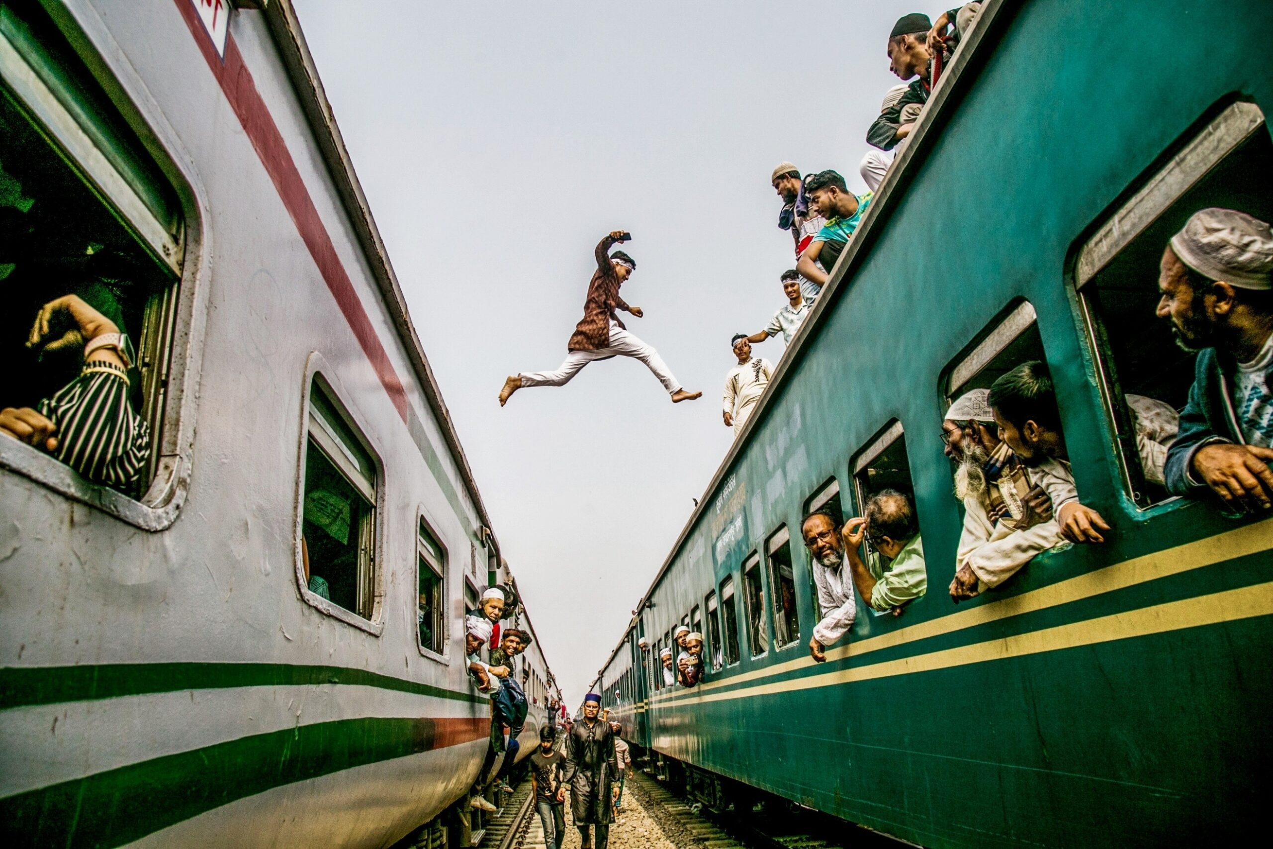 Rayhan Ahmed — Tongi, Dhaka, Bangladesh. A young devotee jumps between two stationary trains as thousands of passengers make their way to the Bishwa Ijtema.