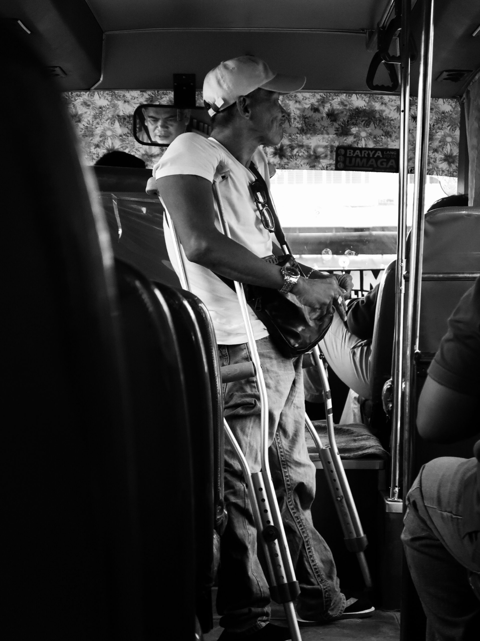 John Leo Comia — Manila, Philippines. Inside a moving Metro Manila bus, a commuter on crutches courageously balances and prepares to alight.
