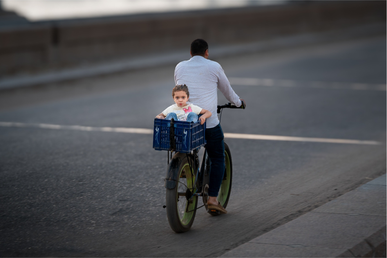 Ahmed Abdallah — Burullus, Egypt. A young girl sits in a bicycle crate as she rides with her father through the streets of Burullus.
