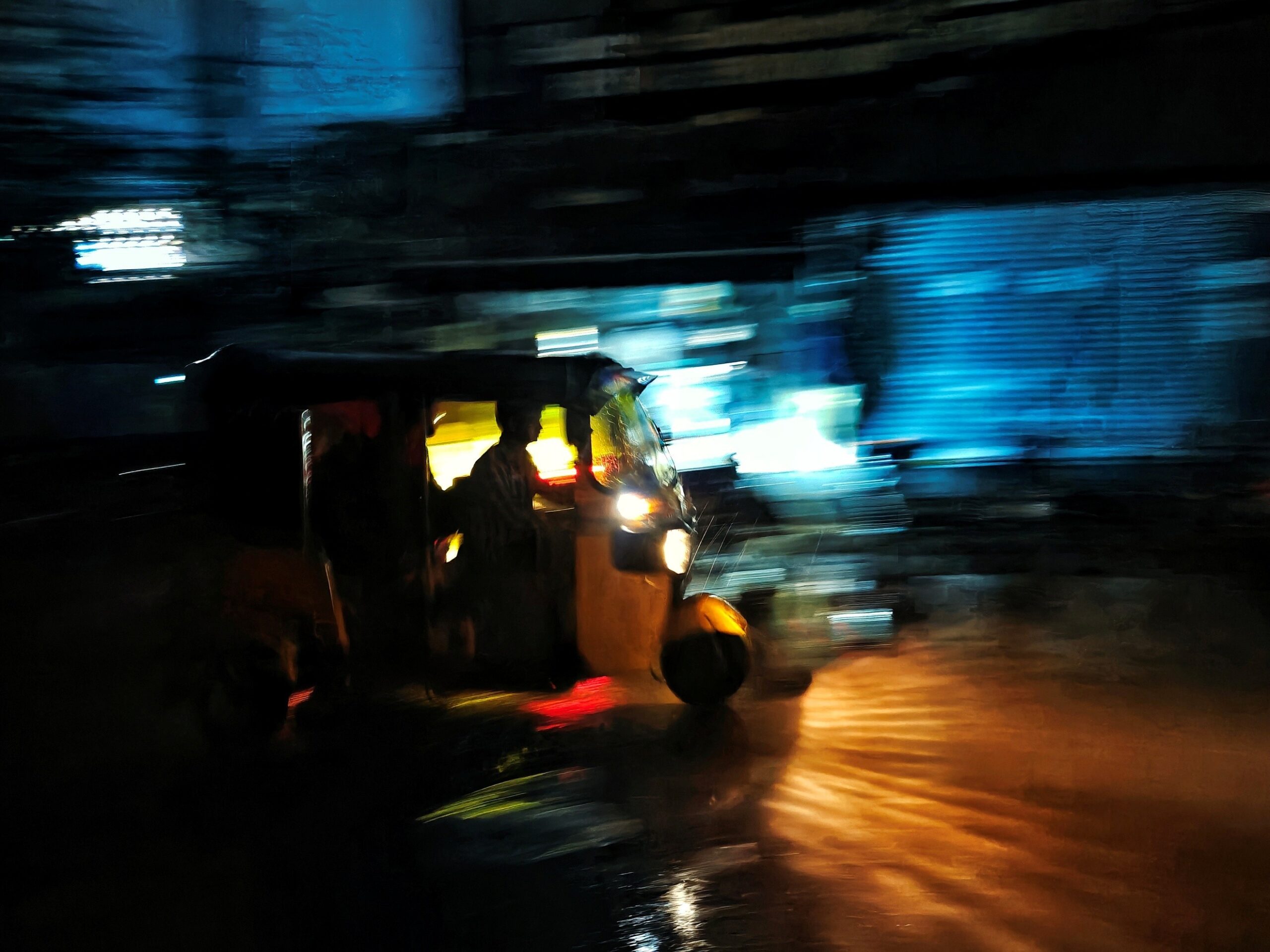 Ayanava Sil — Hyderabad, India. On a rainy night in Hyderabad, an auto-rickshaw moves through the wet streets, carrying passengers.