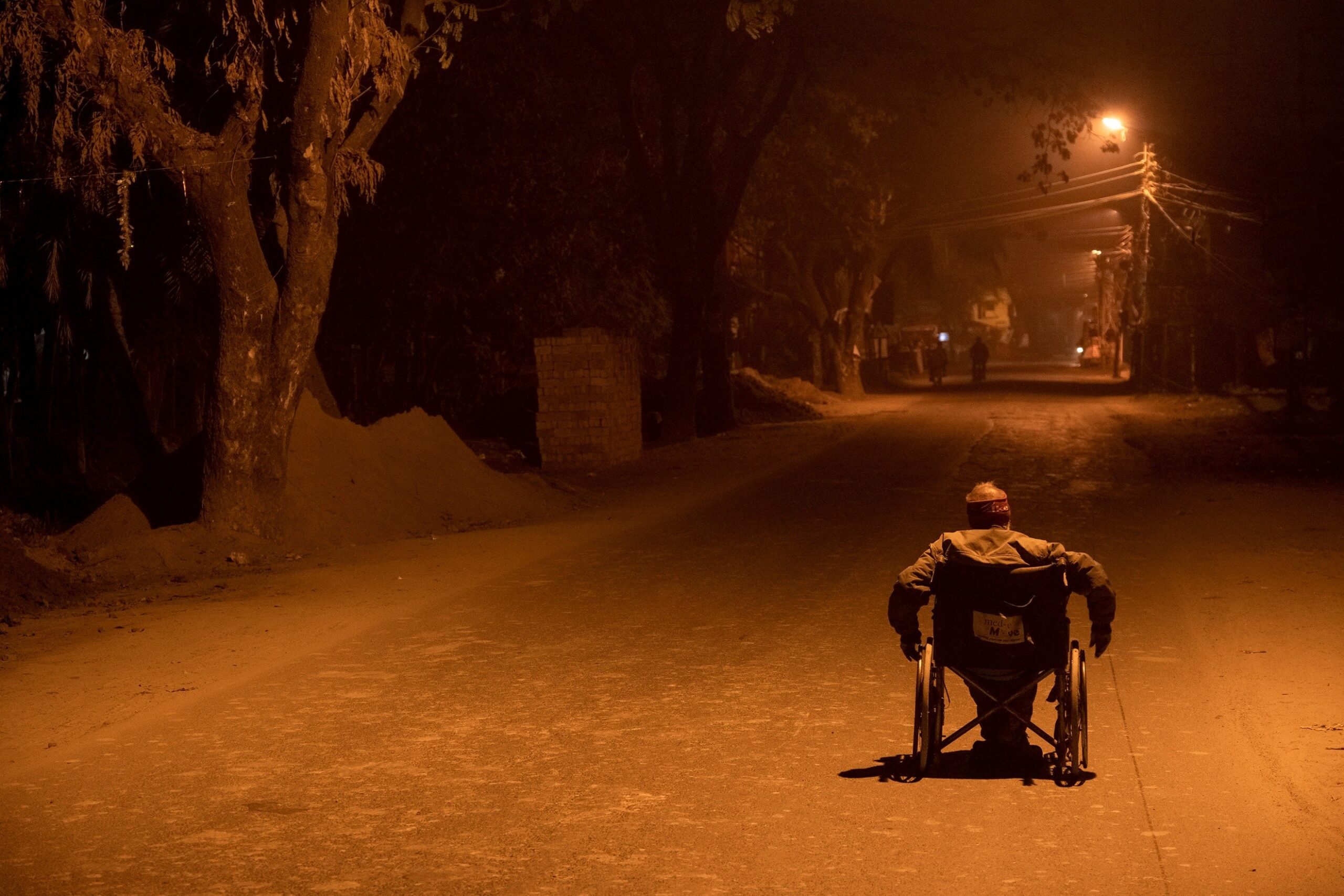 Sudip Maiti — Kolkata, India. A man rides his wheelchair on a suburban road outside Kolkata — disabled populations still suffer from unequal access to roads.
