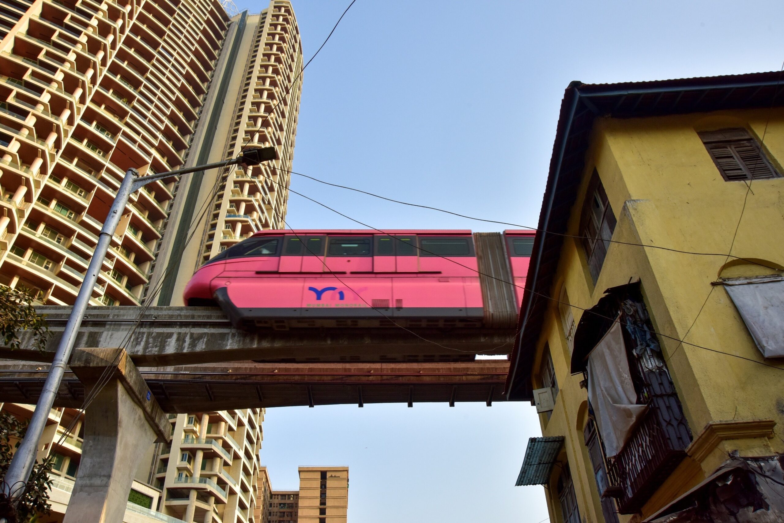Sandeep Rasal — Mumbai, India. A Mumbai Monorail glides past a decades-old chawl and newly built high-rise residential towers.